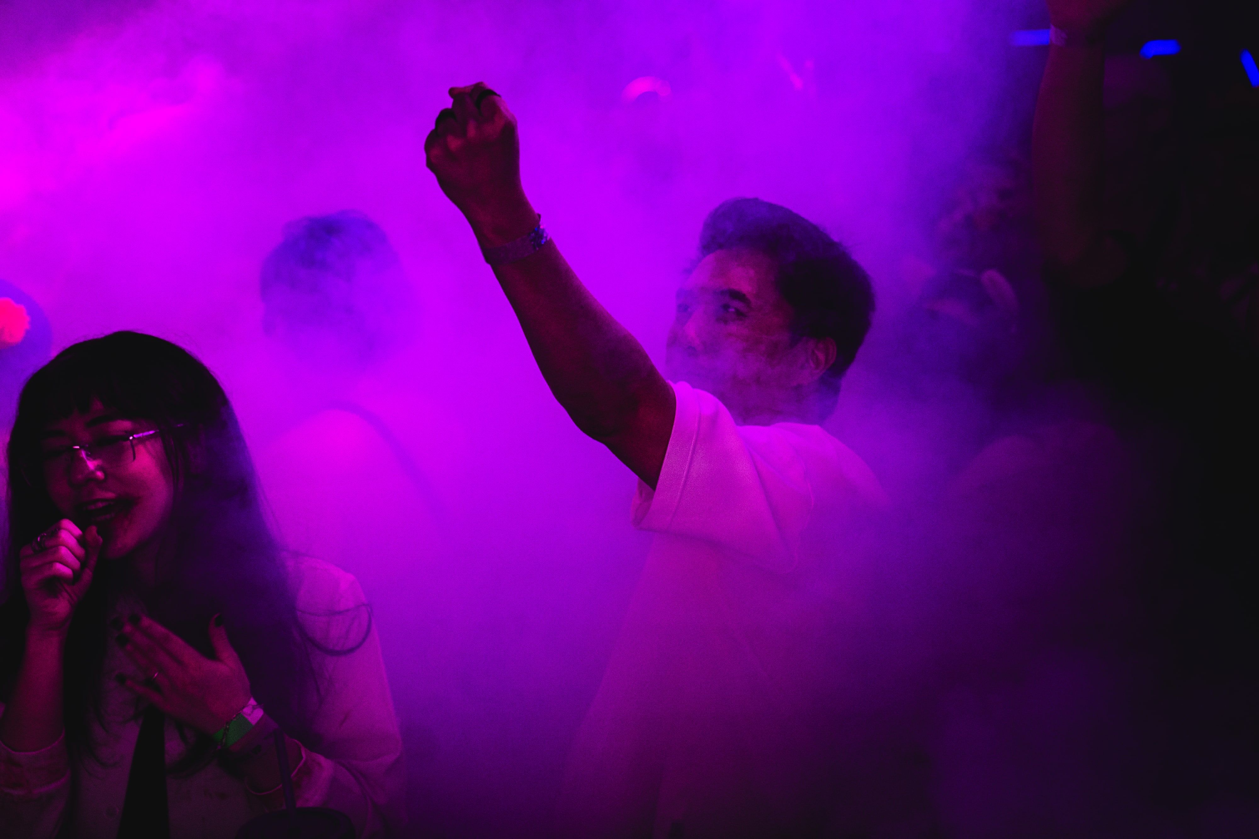 Participantes em meio à iluminação colorida da festa.