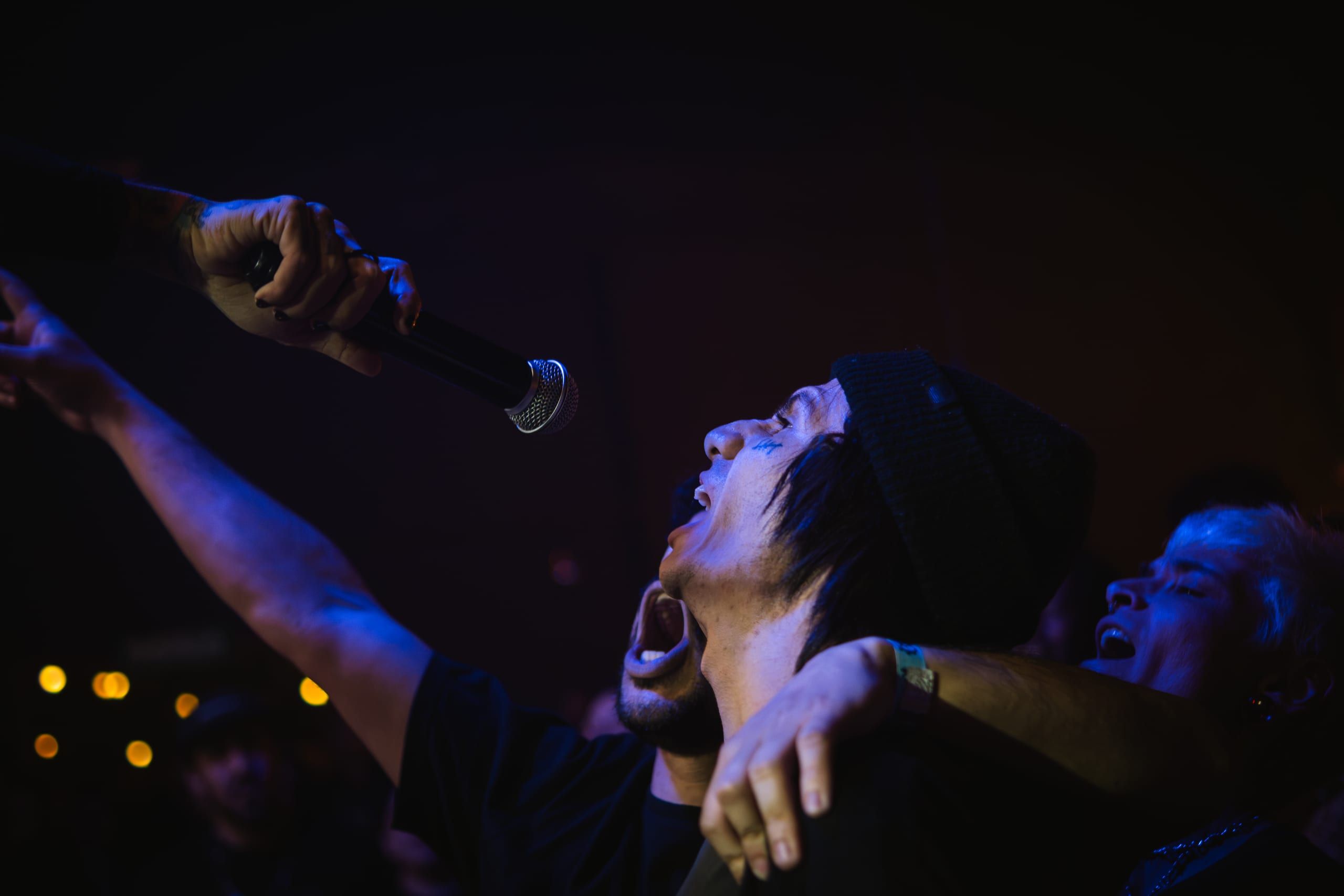 Pessoa canta junto a braços erguidos diante do palco.