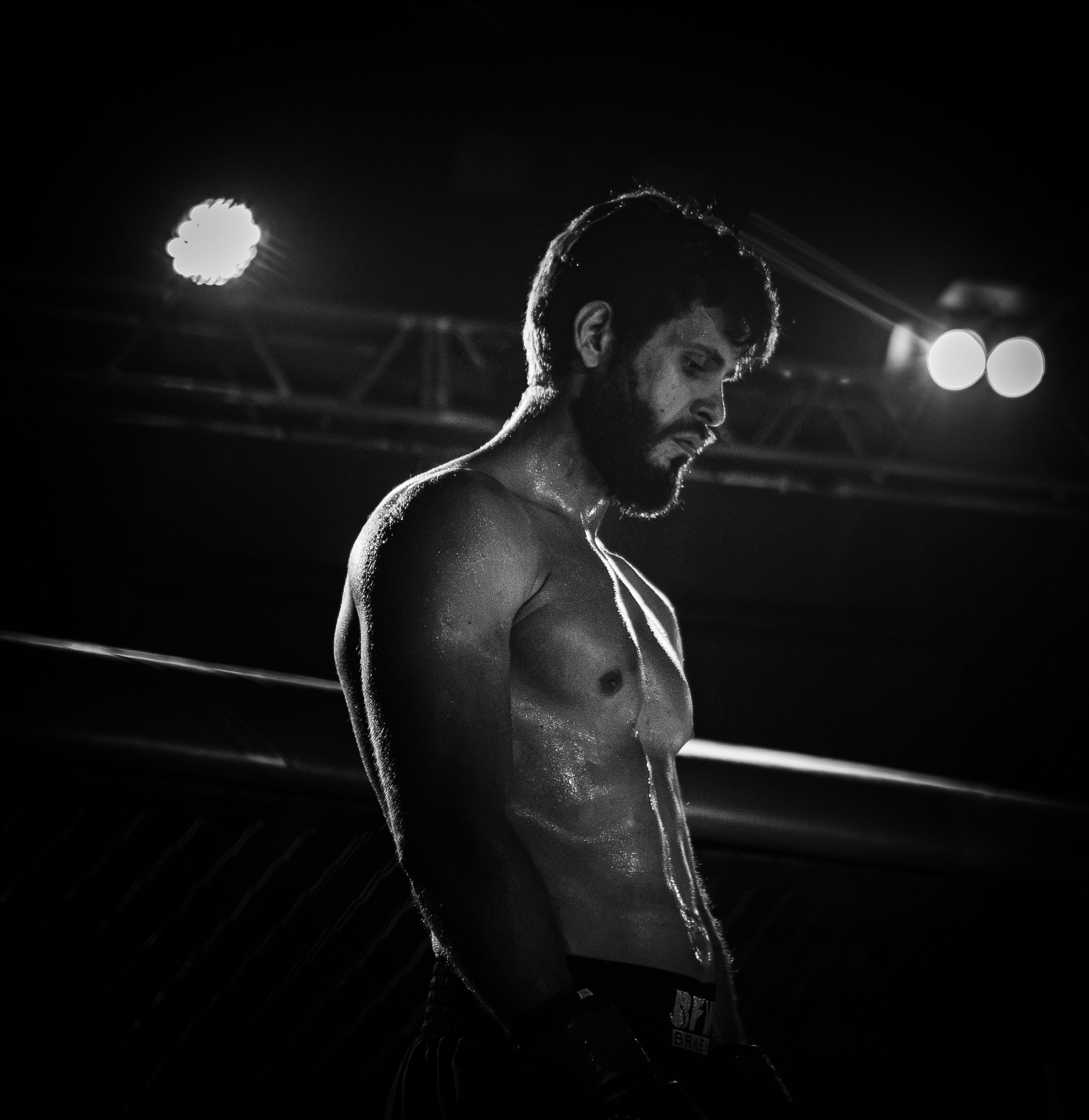 Caio Martins em pé no ringue, iluminado por refletores.