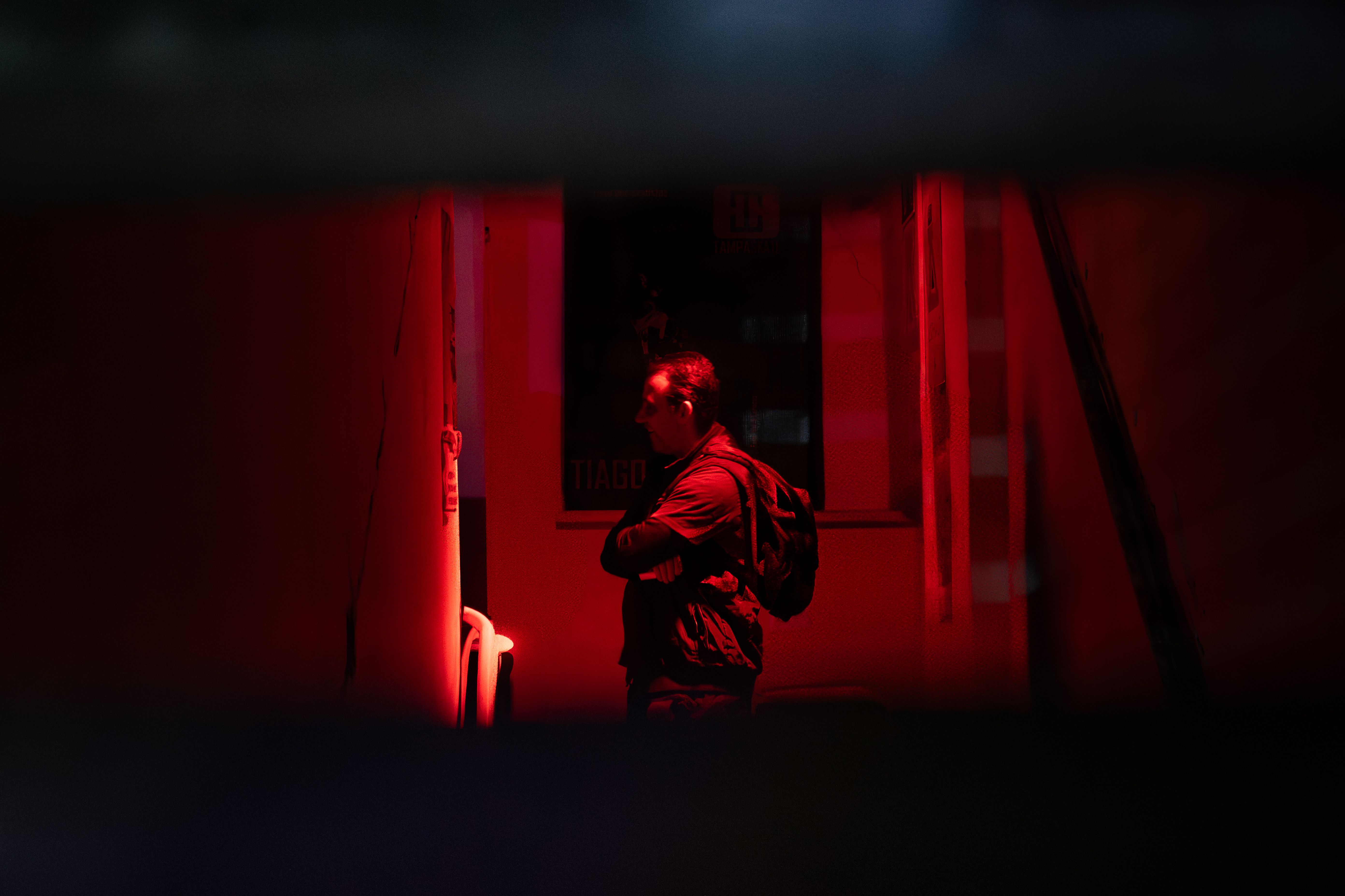 Pessoa de costas observando o ambiente sob iluminação vermelha.
