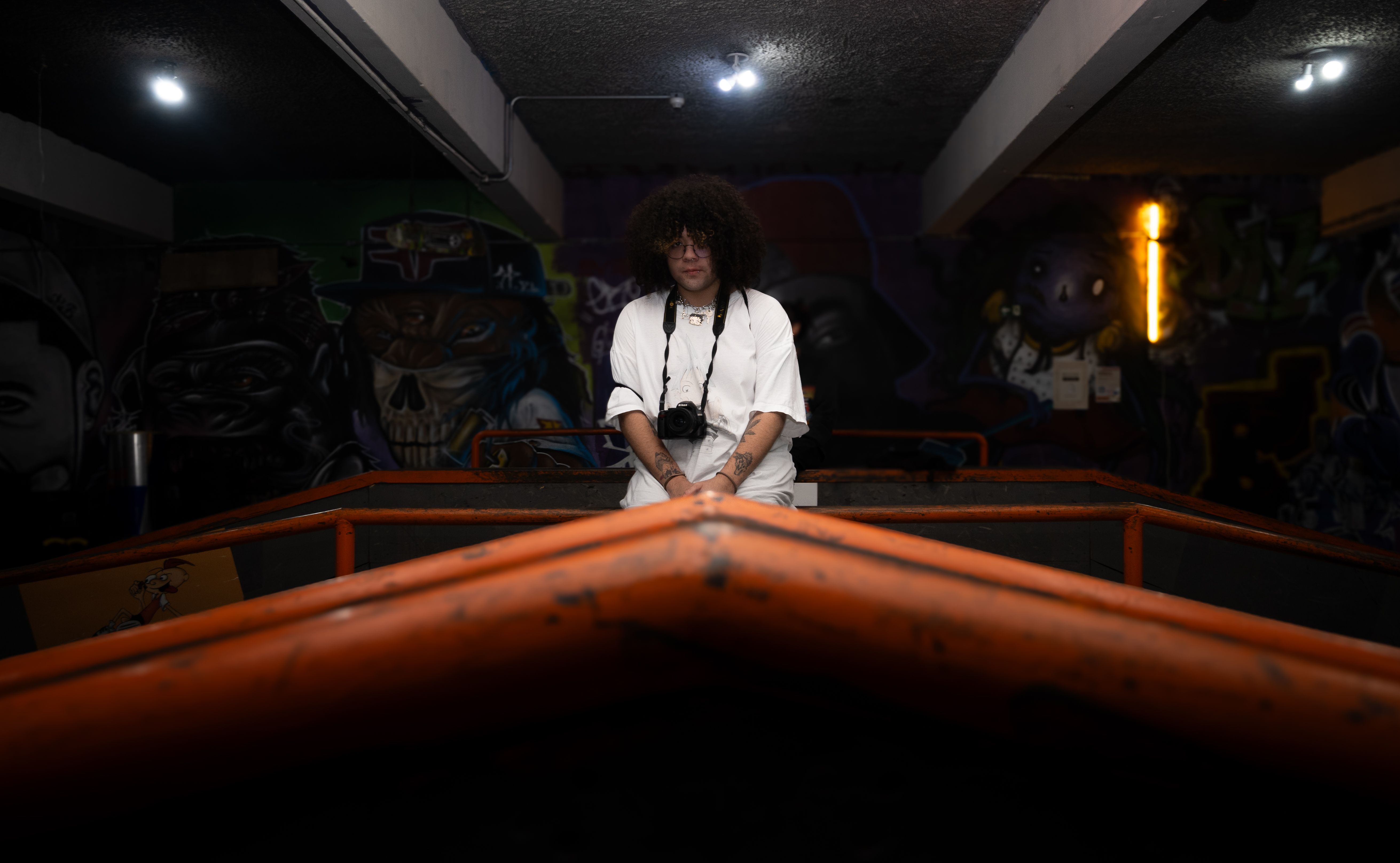 Pessoa apoiada sobre uma estrutura laranja no interior do evento.